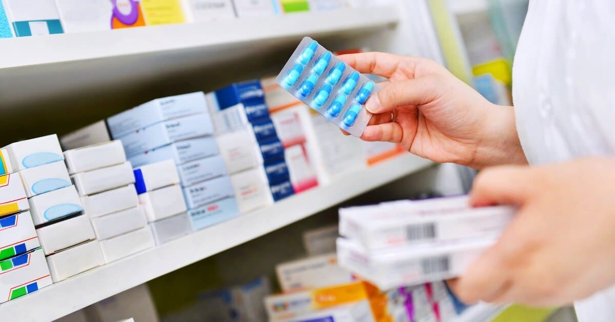 Pharmacist looking at a wall of various medications.