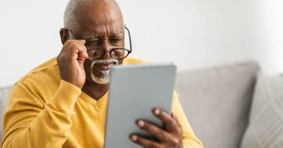 Man having difficulty reading a web page on his tablet.