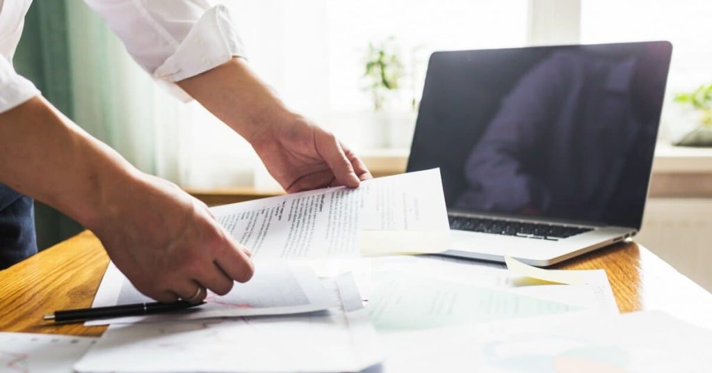 Man reviewing audits at a desk with his computer. 