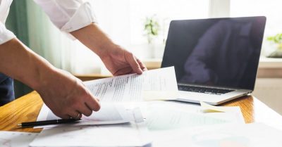 Man reviewing audits at a desk with his computer.