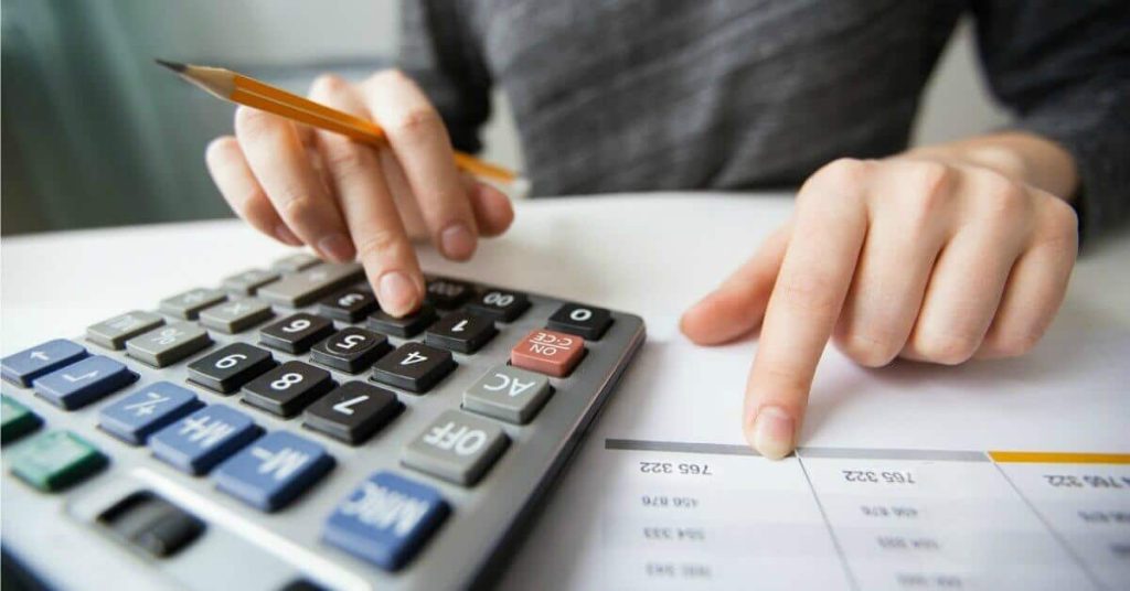 Woman using a calculator to calculate bills being paid.