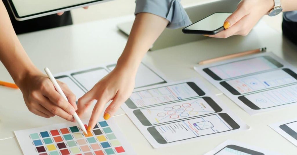 App developers stand over and discuss app plans.