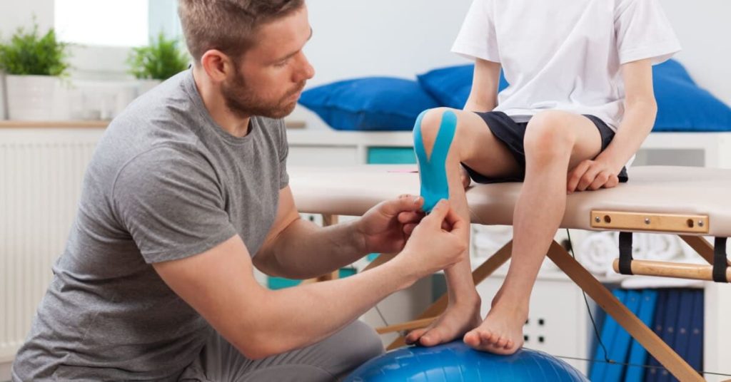 Physical therapist placing recovery tape on a patient.