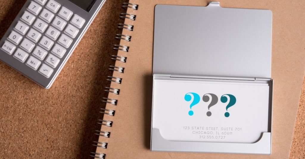 Business card on a table with notebook and calculator.