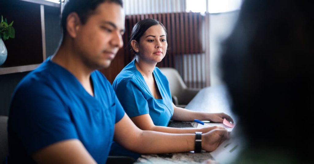 Two healthcare professionals in a business meeting, listening.