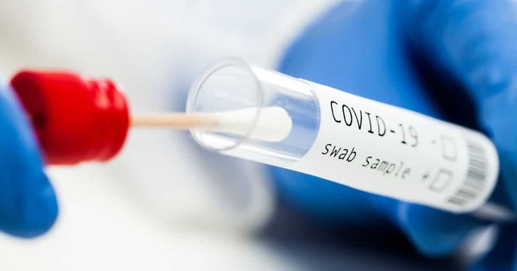 COVID-19 swab sample being inserted in test tube.