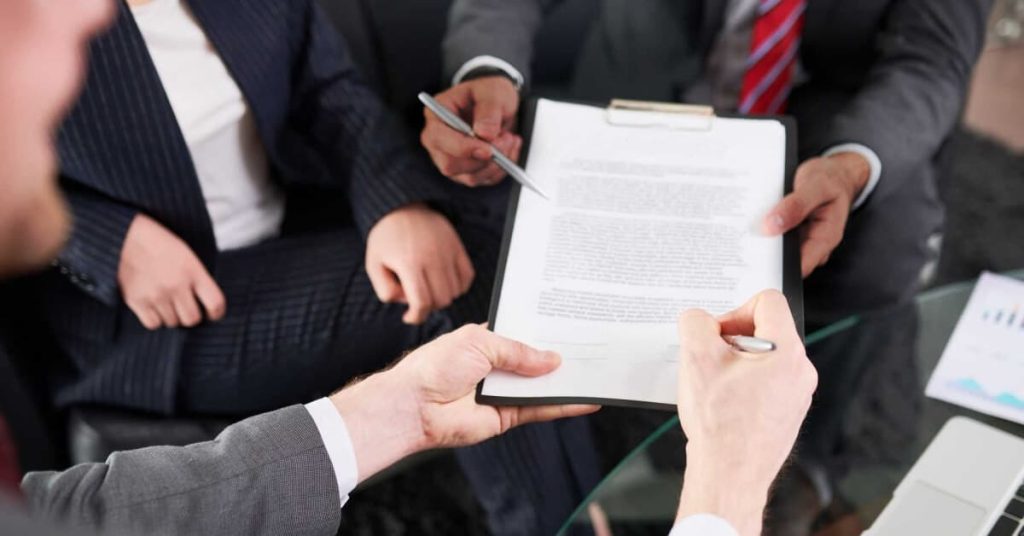 Business owners reading and signing an Asset Purchase Agreement.