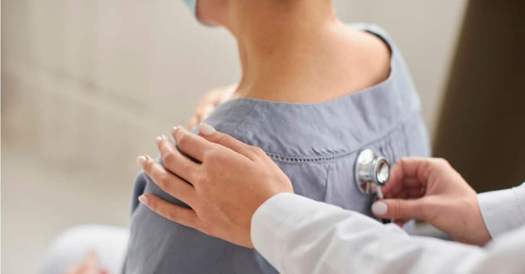 Doctor listening to patient's heartbeat with stethoscope.