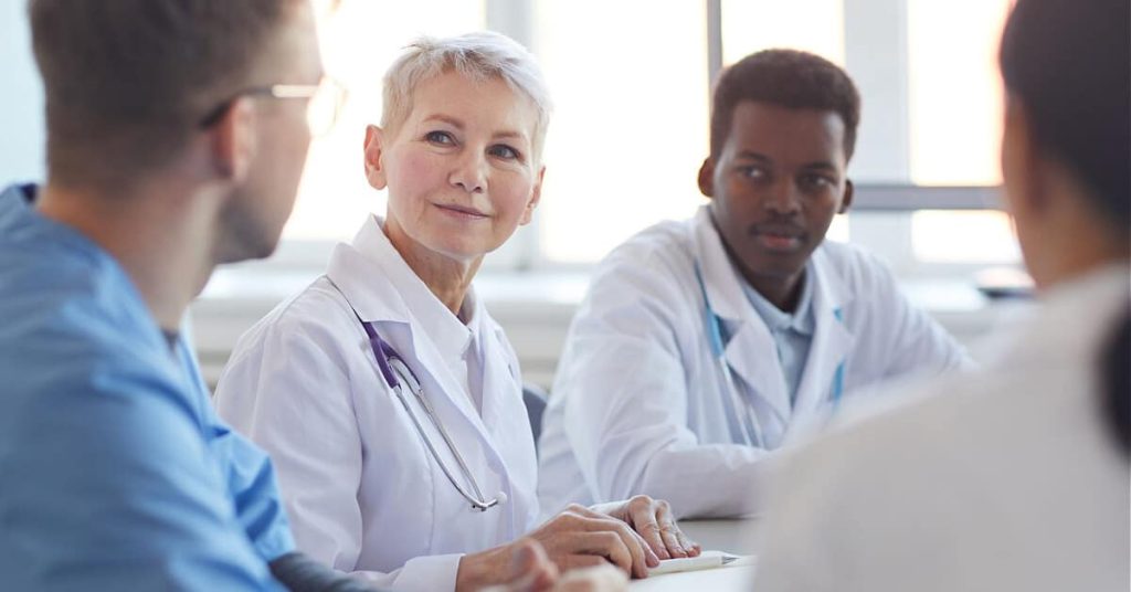A team of four multidisciplinary healthcare professionals in a meeting.