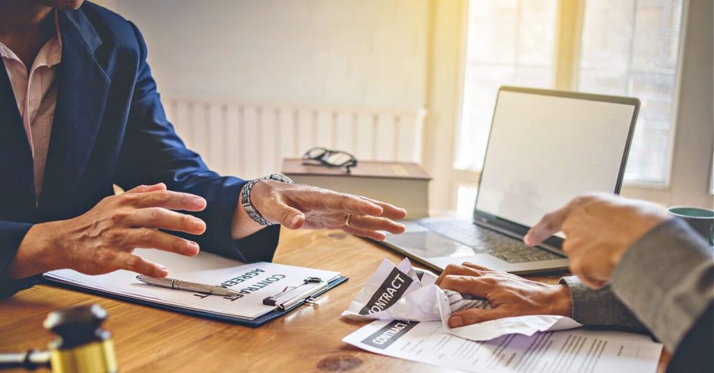 Two men sitting at a desk having a contract displute.
