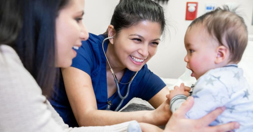 Smiling nurse practitioner with a woman and her baby.