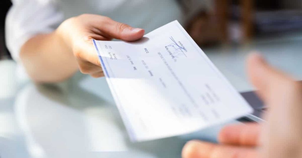 Person handing another person a paycheck