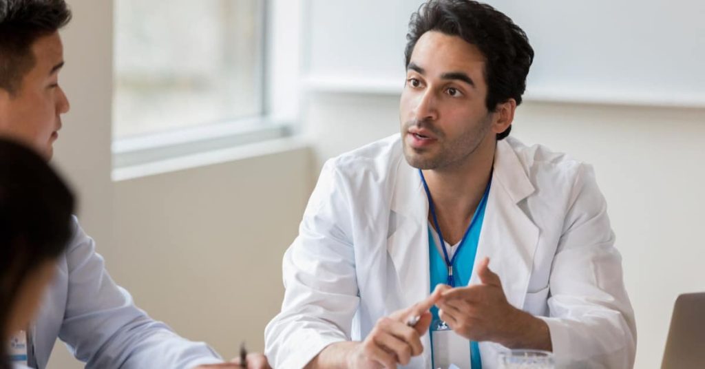 A male physician speaking to non-licensed executives.