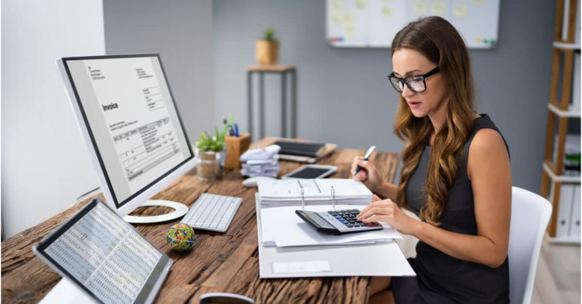 A woman sitting at a desk reviewing healthcare invoices.