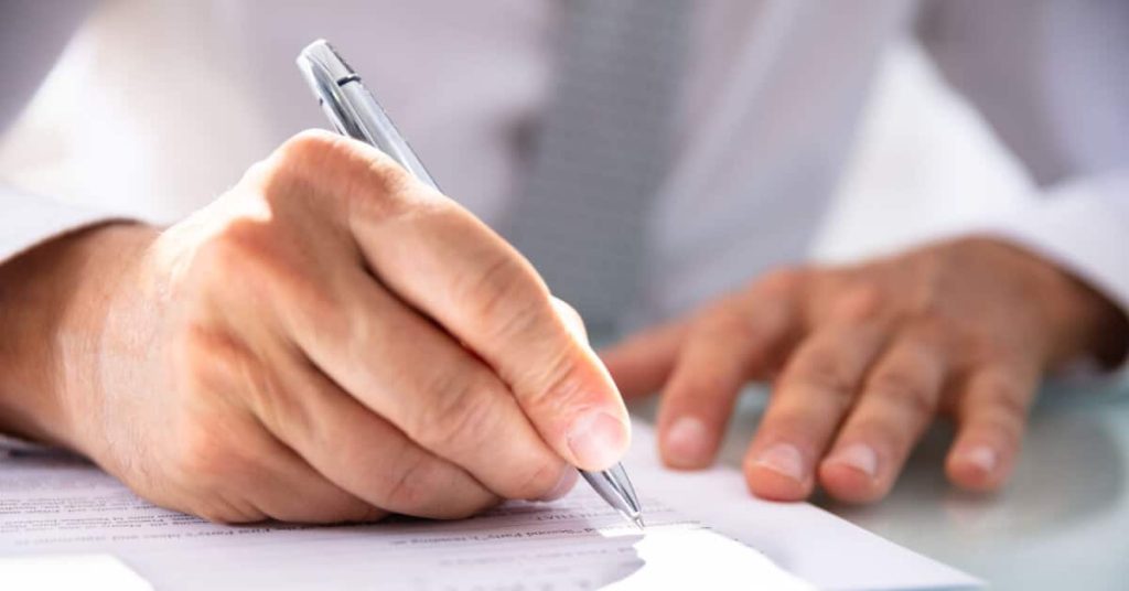 Closeup of hands of person filling out a form.