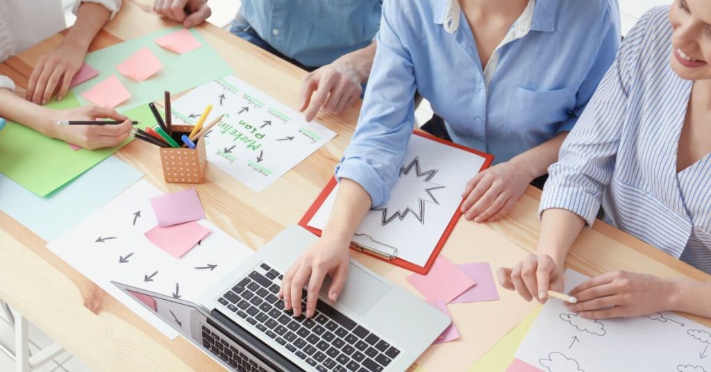A group of people sitting at a table with a laptop and marketing diagrams