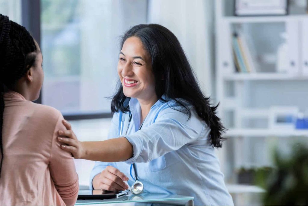Smiling doctor touching the shoulder of a patient.