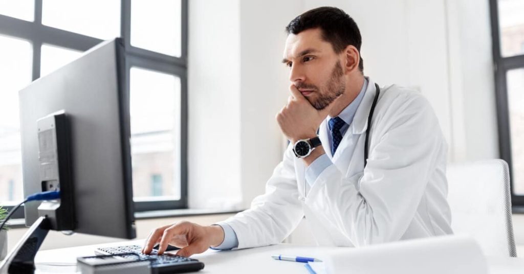 Physician sitting at computer.