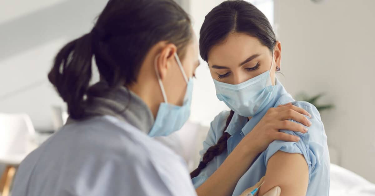 Healthcare professional giving a vaccine to a female patient.