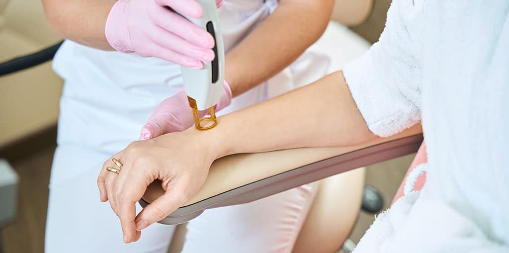 technician performing laser hair removal on a woman's arm