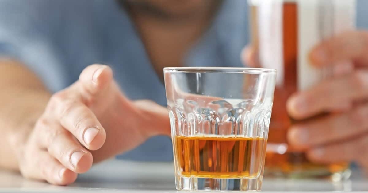 A healthcare professional reaching for a glass of alcohol.