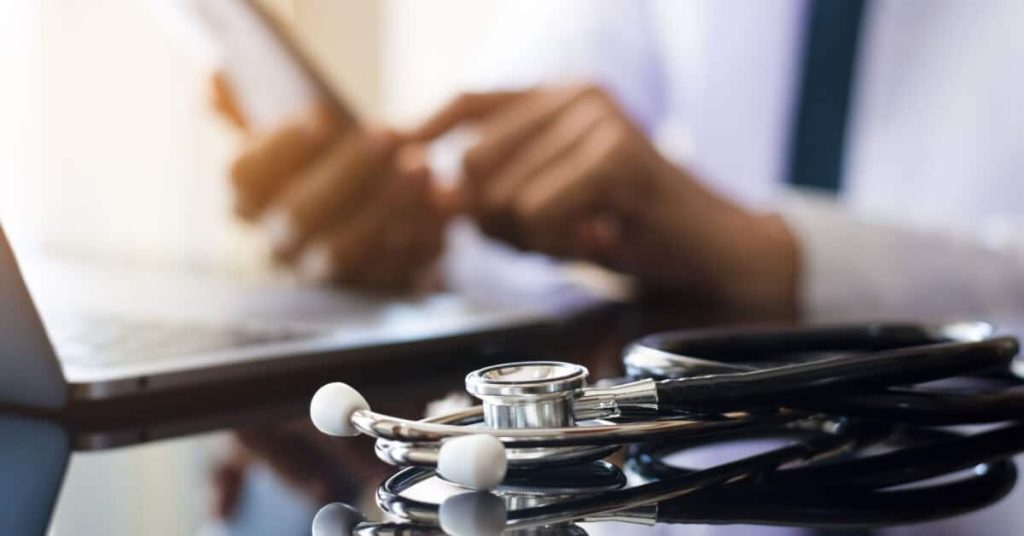 A closeup of a physician's hands using a mobile phone.