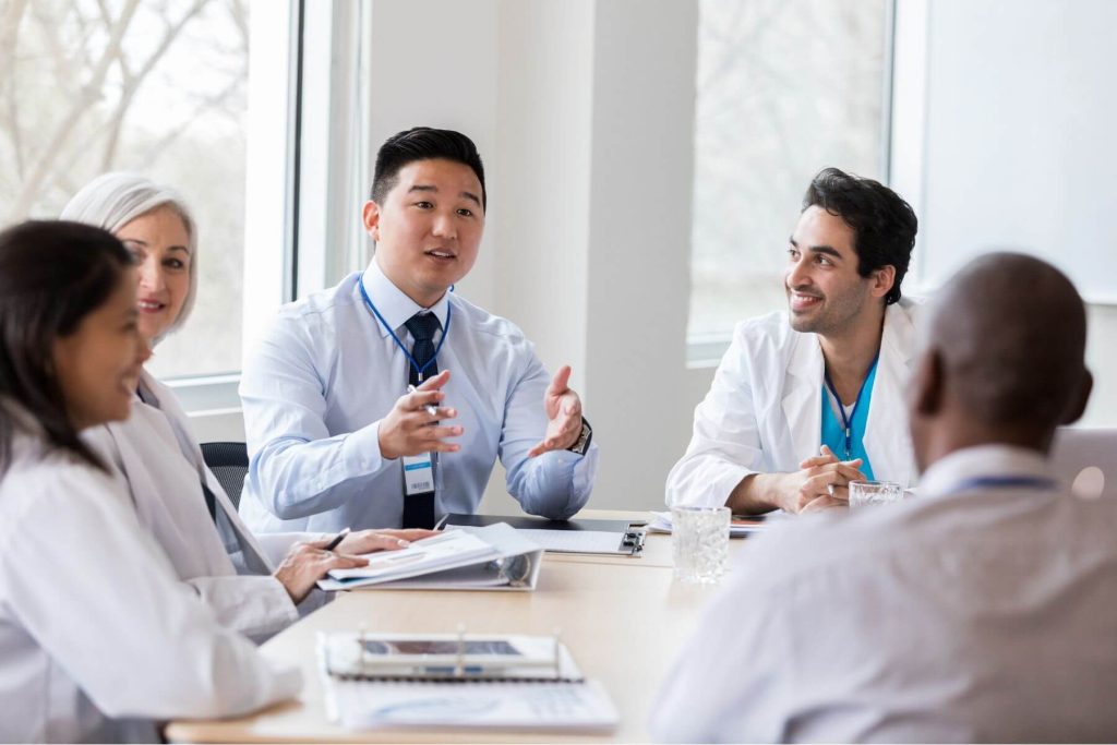 Group of physicians sitting around a conference room table.