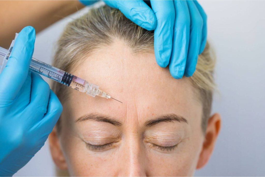 Woman getting Botox injected into her forehead.