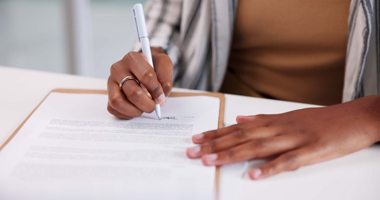 Person signing an MSO management services agreement with a pen at a desk