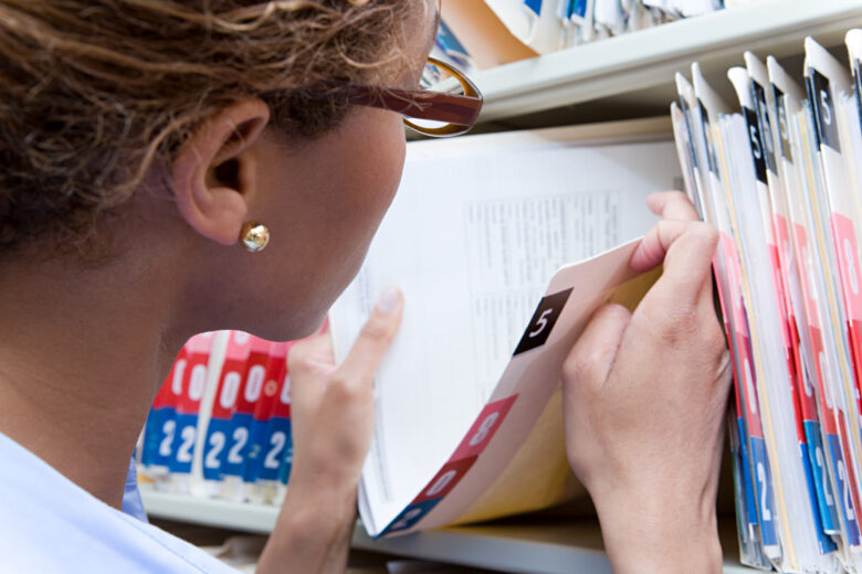 Healthcare worker retrieving a paper patient record, illustrating HIPAA compliance for private practices