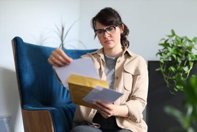 Behavioral health provider reviewing an insurance audit letter while seated in a chair.