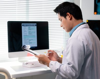 A doctor with a notepad enters personal health information into a computer, potentially raising questions about AI HIPAA compliance.