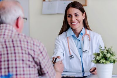 An older patient hands a female doctor a credit card to cover the cost of his direct primary care arrangement.
