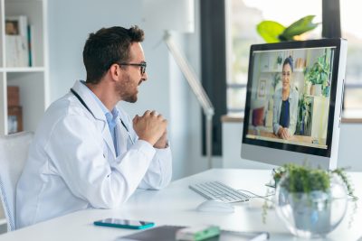 Male physician discussing prescribing controlled substances through telehealth with a female patient.